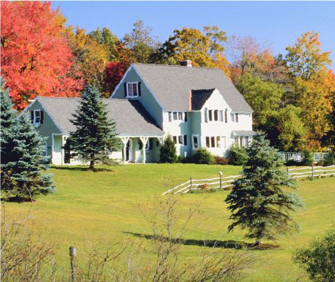 A large sprawling countryside home with a fence and trees