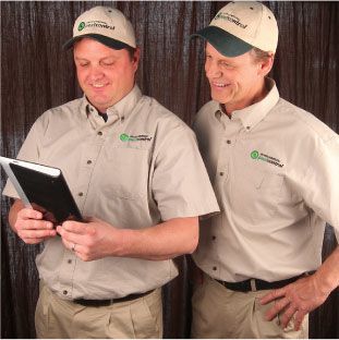 Two smiling male Environmental Pest Control professionals looking over a report