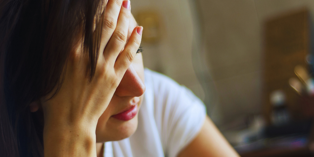A stressed out woman holding her head in her hand